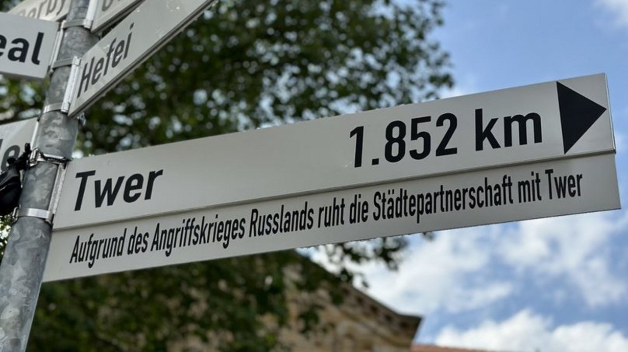 Der Wegweiser nach Twer auf dem Platz der Städtefreundschaften in Osnabrück ist durch ein Zusatzschild ergänzt worden: „Aufgrund des Angriffskriegs Russlands ruht die Städtepartnerschaft mit Twer.“ 